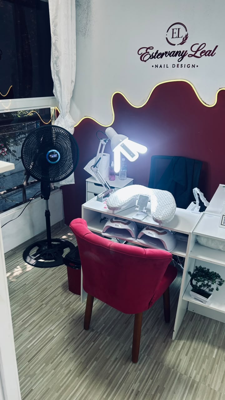 Mesa de atendimento do studio com luminária, cabines e cadeira vermelha